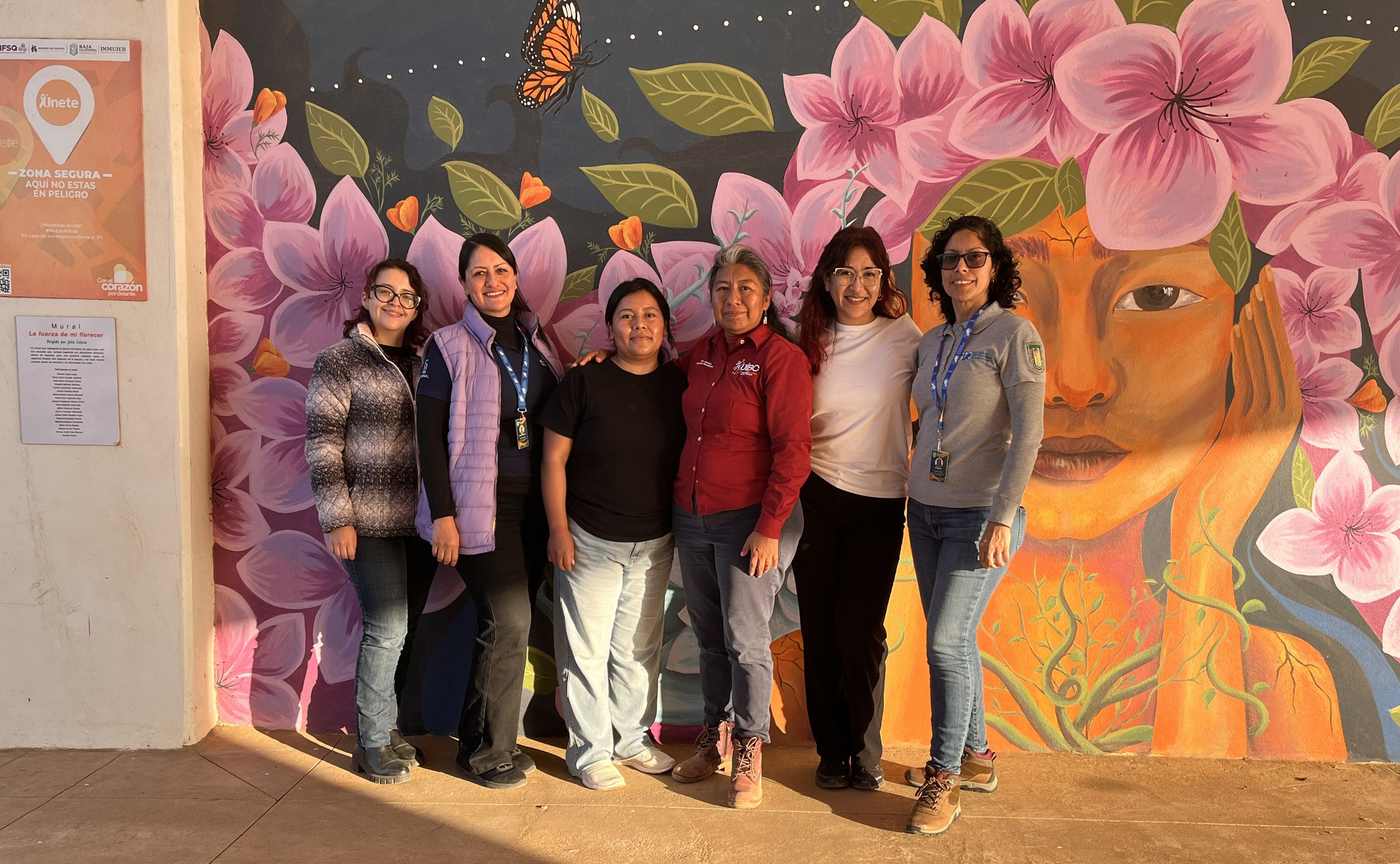 Equipo de divulgación frente a un mural comunitario